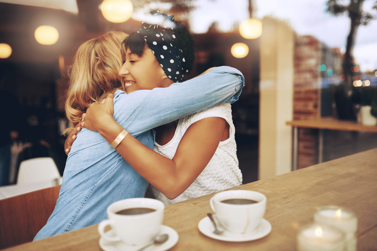women hugging in coffee shop